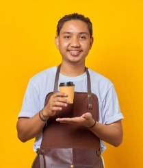 Asian barista smiling while holding a coffee cup against a bright yellow background.